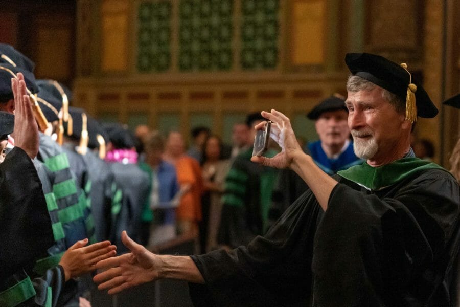 WesternU faculty shaking graduates' hands as they process to the PCA stage. WesternU faculty shaking graduates' hands as they process to the PCA stage.