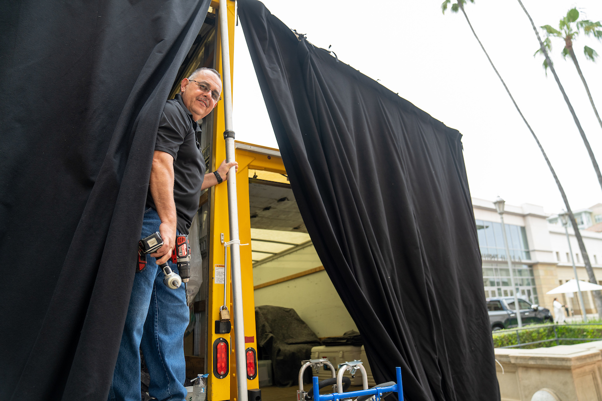 University employee standing on a truck behind a black curtain preparing for the ceremony. University employee standing on a truck behind a black curtain preparing for the ceremony.