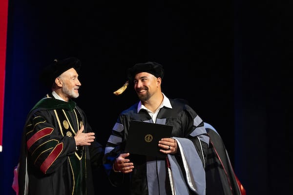 Graduate receives diploma from President before proceeding to family hooders. Pictured here is a graduate who has just received their stage diploma from the president and their dean and now they are making their way across stage to meet their family on stage to receive their hood.